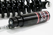 A close-up side shot of an RWD V-Twin RS-2 reservoir, featuring a black body with red and white RWD branding, connected to a silver hose, with a black spring in the background.